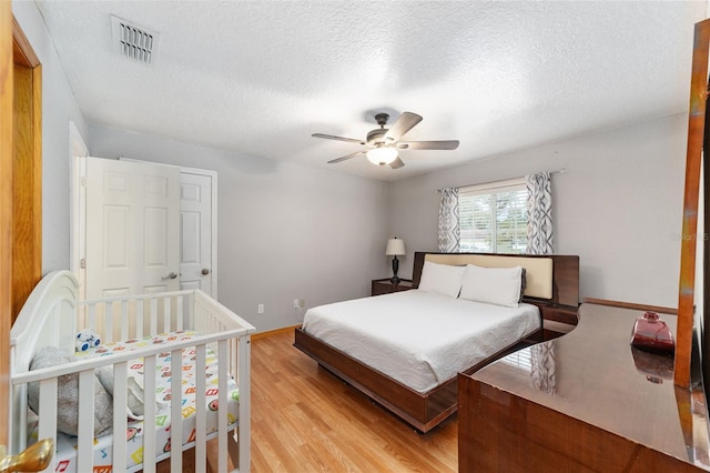 bedroom with light hardwood / wood-style floors, ceiling fan, and a textured ceiling