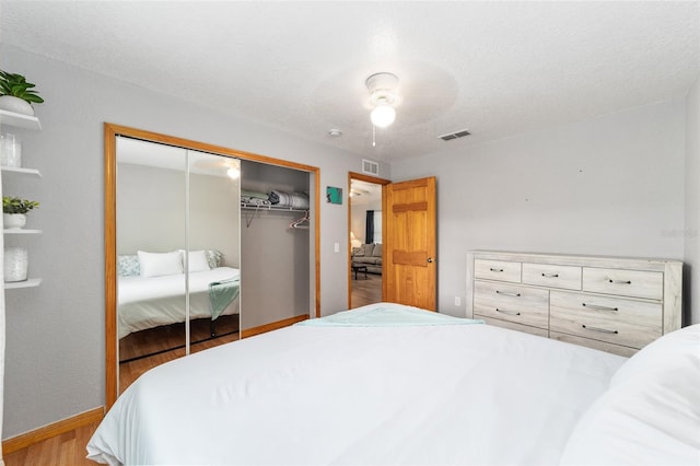 bedroom featuring ceiling fan, a textured ceiling, a closet, and light hardwood / wood-style flooring