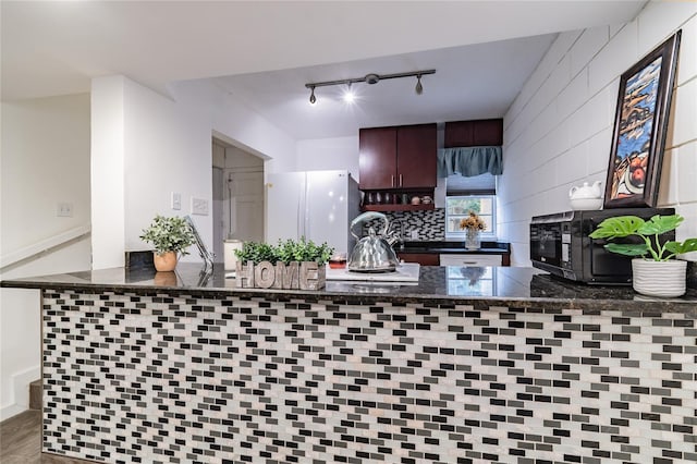 kitchen with tasteful backsplash, dark brown cabinets, kitchen peninsula, and white fridge