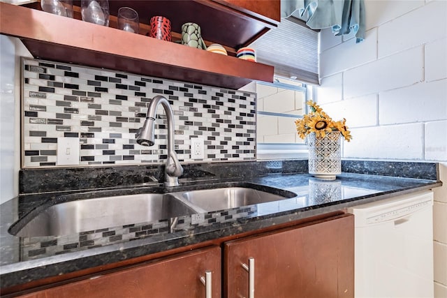 kitchen featuring white dishwasher, dark stone counters, sink, and tasteful backsplash