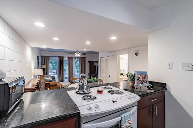 kitchen featuring ceiling fan, dark brown cabinets, dark stone counters, and white range with electric stovetop