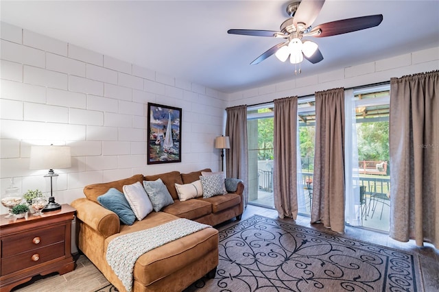 living room with ceiling fan and tile walls