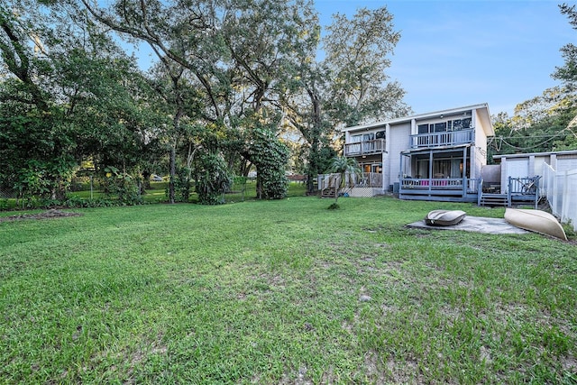 view of yard featuring a balcony, a deck, and a storage shed