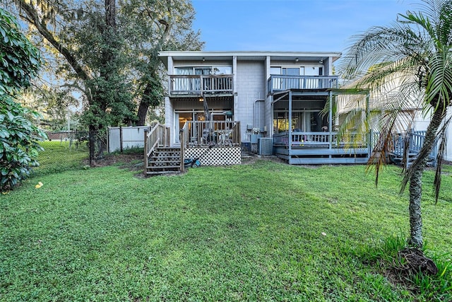 rear view of house with central air condition unit, a yard, a balcony, and a wooden deck