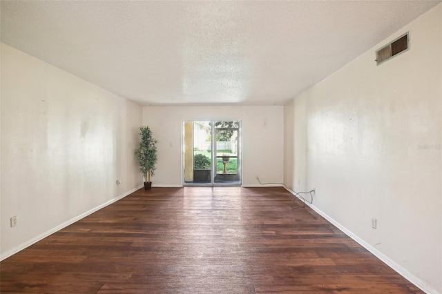 spare room featuring a textured ceiling and dark hardwood / wood-style flooring