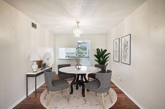 dining area with a textured ceiling, wood-type flooring, and a chandelier