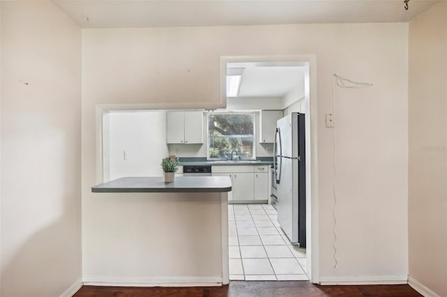 kitchen featuring light tile patterned flooring, white cabinetry, stainless steel appliances, and kitchen peninsula