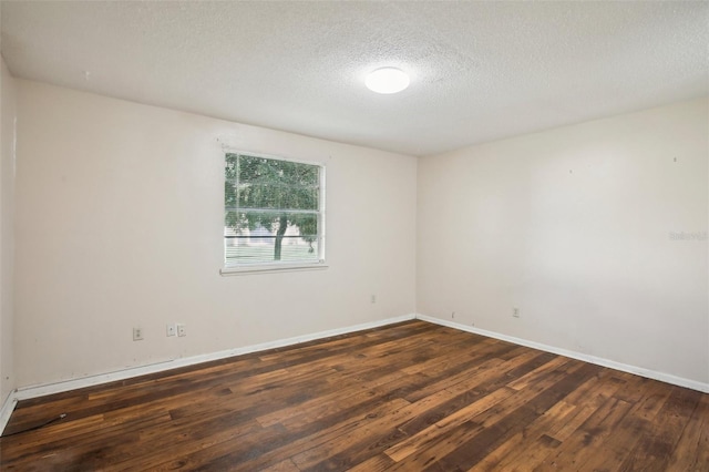 spare room with a textured ceiling and dark wood-type flooring