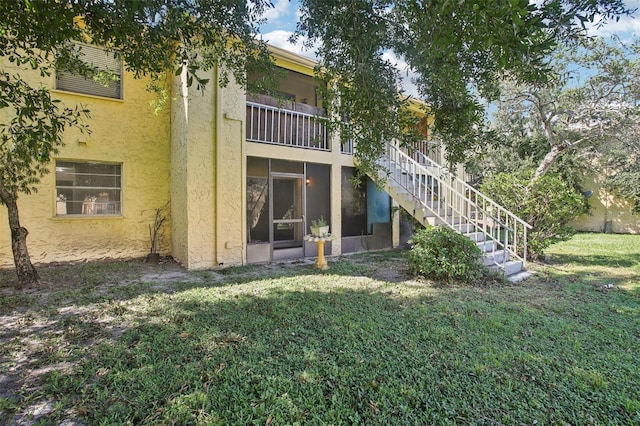 back of house featuring a balcony and a lawn