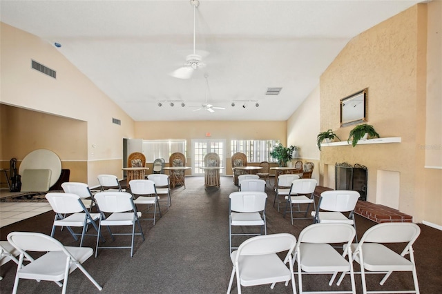 dining room featuring ceiling fan, track lighting, vaulted ceiling, and a large fireplace