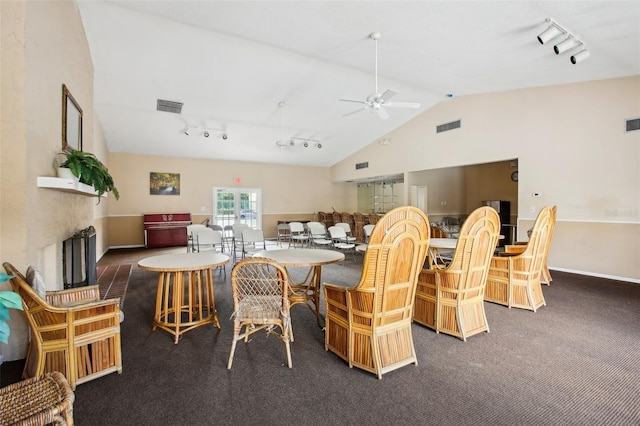 carpeted dining area featuring ceiling fan, lofted ceiling, a fireplace, and track lighting