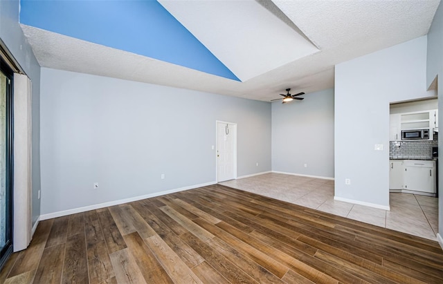 unfurnished living room featuring a textured ceiling, light hardwood / wood-style floors, vaulted ceiling, and ceiling fan