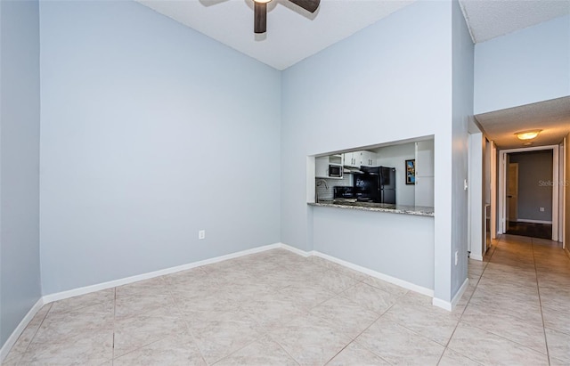 unfurnished living room with a textured ceiling, light tile patterned flooring, ceiling fan, and high vaulted ceiling