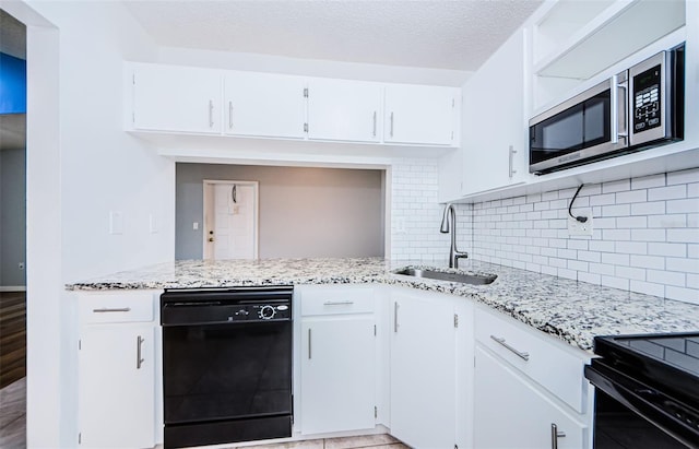 kitchen featuring decorative backsplash, black dishwasher, white cabinetry, and sink