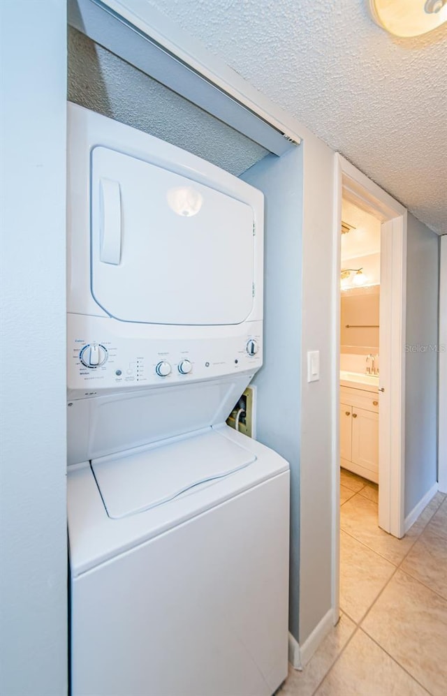 washroom with light tile patterned floors, a textured ceiling, and stacked washer and dryer