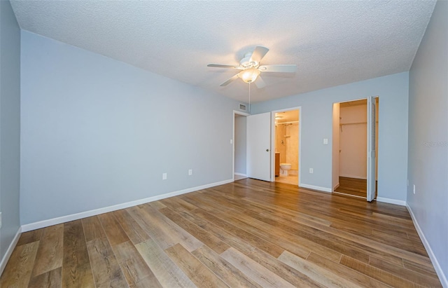 unfurnished bedroom featuring connected bathroom, a closet, a textured ceiling, ceiling fan, and light hardwood / wood-style flooring