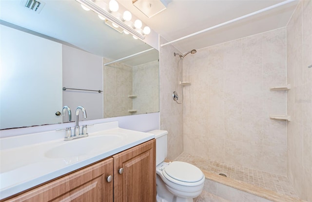 bathroom with tiled shower, vanity, toilet, and tile patterned floors