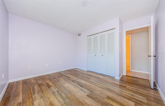 unfurnished bedroom featuring a textured ceiling, hardwood / wood-style floors, and a closet