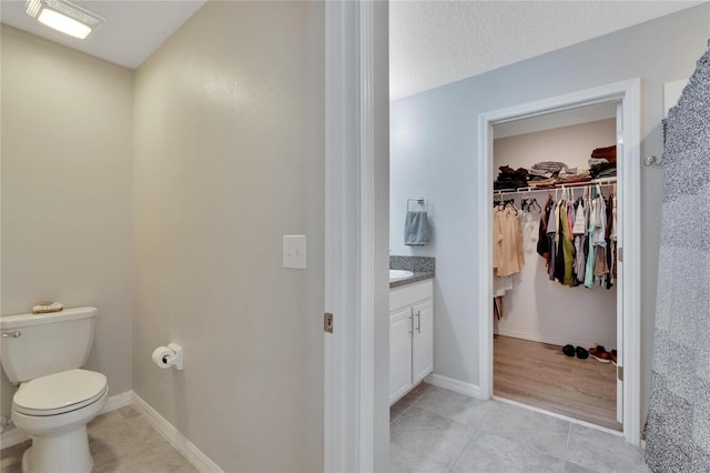 bathroom with a textured ceiling, vanity, and toilet