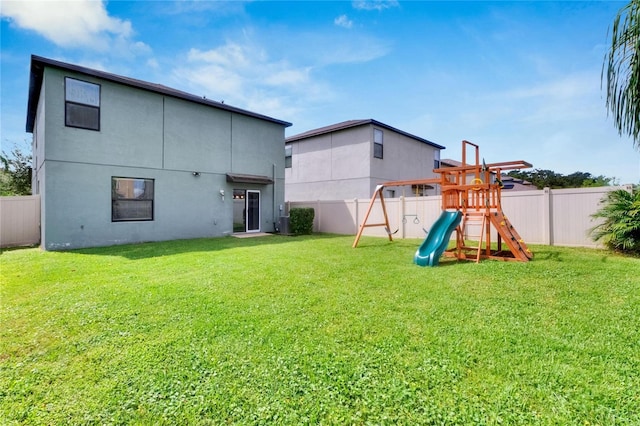 back of property with a playground and a yard