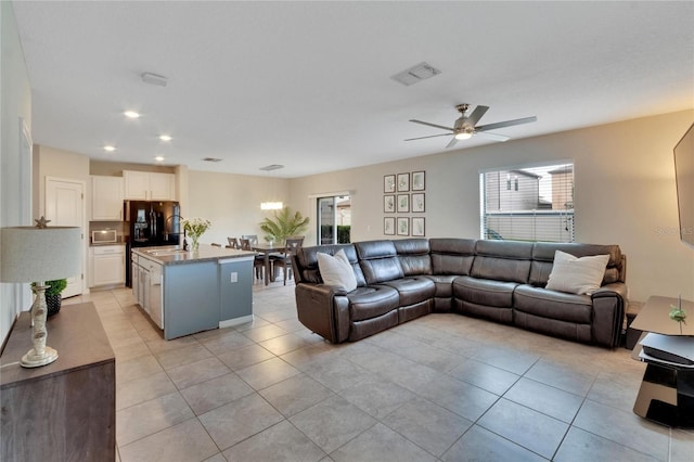 living room with ceiling fan, plenty of natural light, and light tile patterned floors