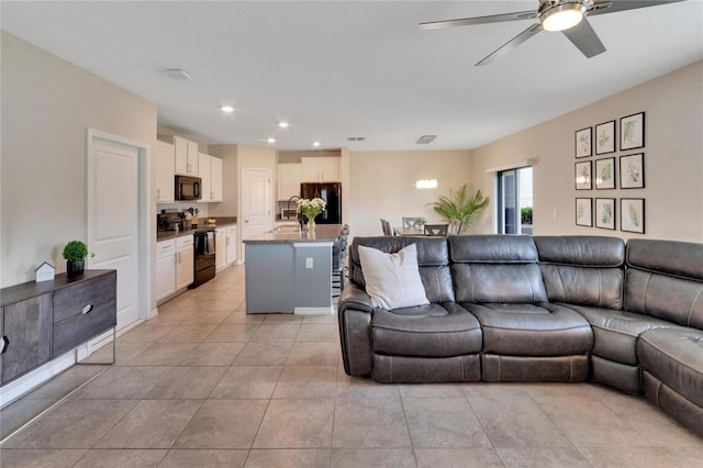 tiled living room with ceiling fan and sink