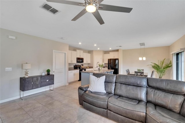 tiled living room featuring ceiling fan and sink