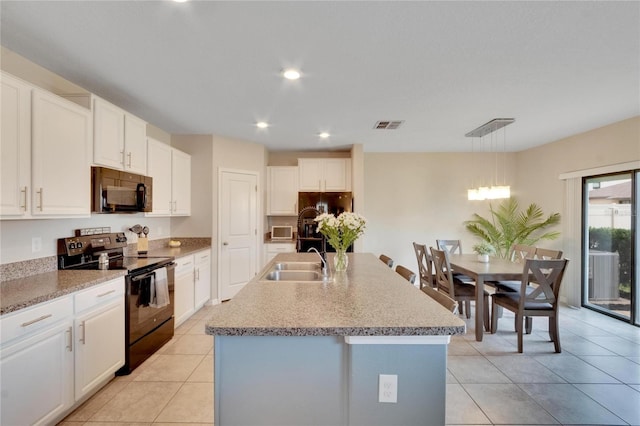 kitchen featuring sink, hanging light fixtures, an island with sink, white cabinets, and black appliances