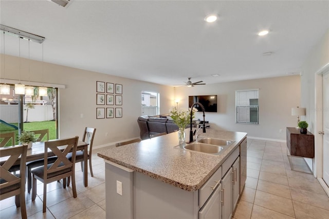 kitchen featuring ceiling fan, sink, stainless steel dishwasher, an island with sink, and light tile patterned flooring