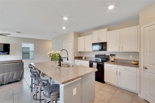 kitchen with white cabinetry, sink, an island with sink, a kitchen bar, and black appliances