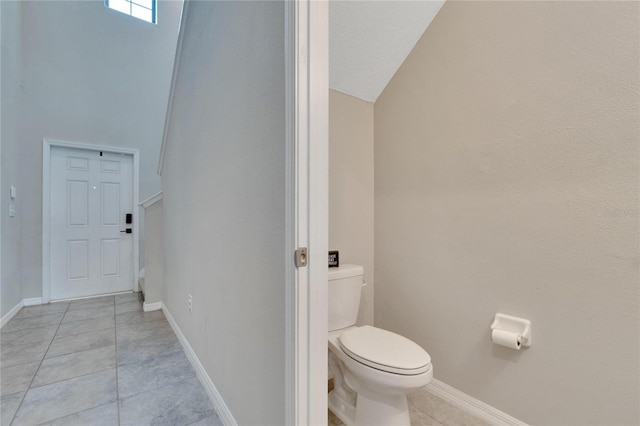 bathroom with tile patterned floors, lofted ceiling, and toilet