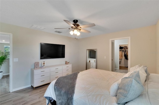 bedroom featuring ensuite bathroom, a walk in closet, ceiling fan, light hardwood / wood-style floors, and a closet