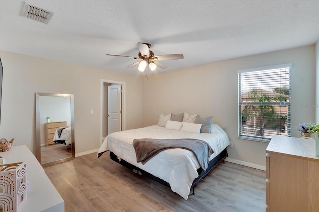 bedroom featuring a textured ceiling, light hardwood / wood-style flooring, and ceiling fan