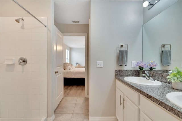 bathroom featuring tile patterned floors, vanity, and a tile shower