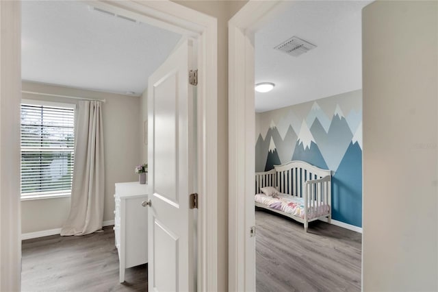 bedroom with hardwood / wood-style floors and a nursery area