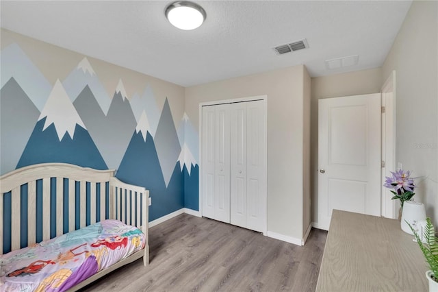 bedroom with a closet, a textured ceiling, and hardwood / wood-style flooring