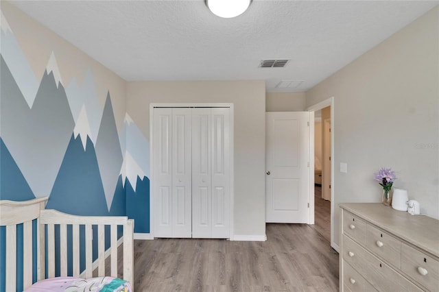 bedroom featuring a closet, light hardwood / wood-style floors, and a textured ceiling