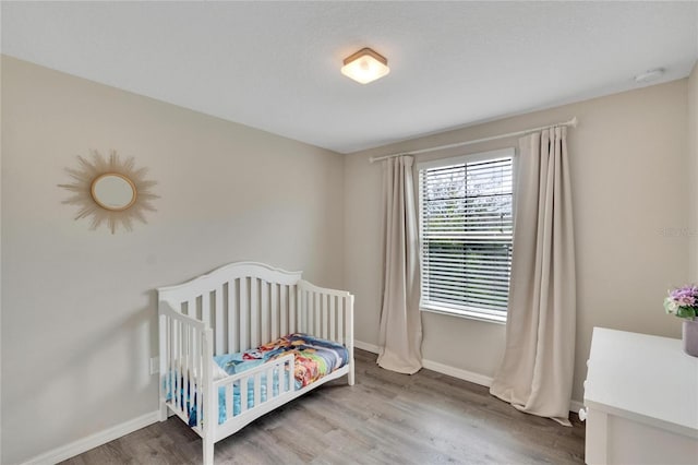 bedroom featuring wood-type flooring and a nursery area