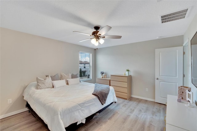 bedroom with ceiling fan, light wood-type flooring, and a textured ceiling