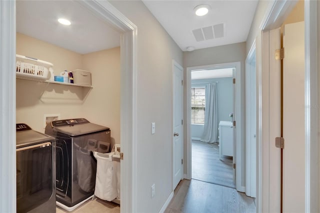 clothes washing area featuring independent washer and dryer and light hardwood / wood-style flooring