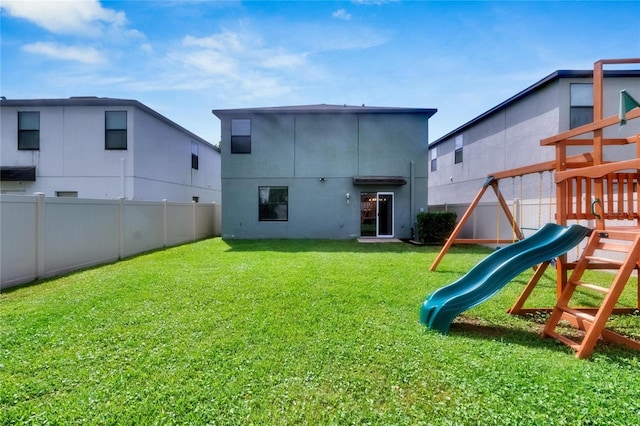 rear view of property featuring a playground and a lawn