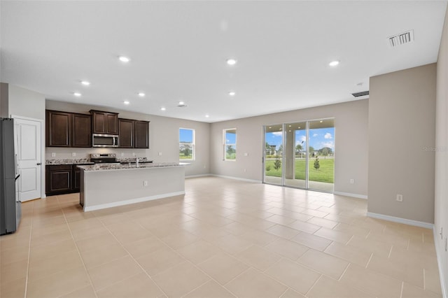 kitchen featuring an island with sink, stainless steel appliances, sink, and light tile patterned floors