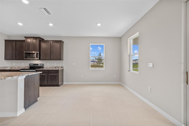 kitchen with appliances with stainless steel finishes, light stone countertops, dark brown cabinets, and light tile patterned floors