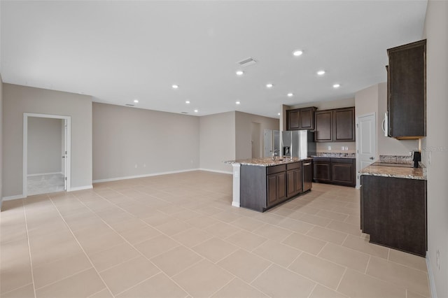 kitchen featuring light stone countertops, appliances with stainless steel finishes, light tile patterned floors, and a center island