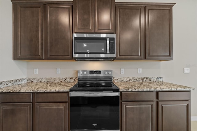 kitchen featuring dark brown cabinetry, light stone countertops, and appliances with stainless steel finishes