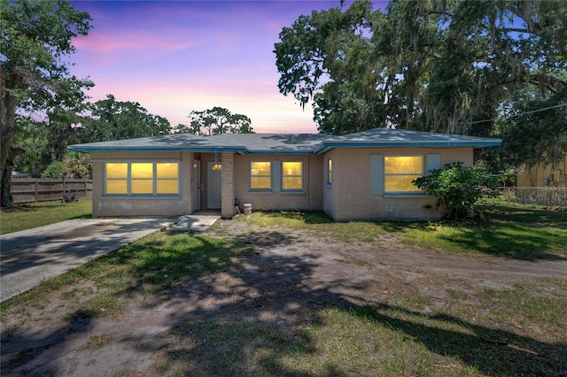 view of front of home featuring driveway, fence, a front yard, and concrete block siding