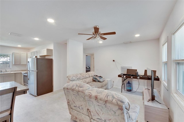 living room with ceiling fan, light colored carpet, and sink