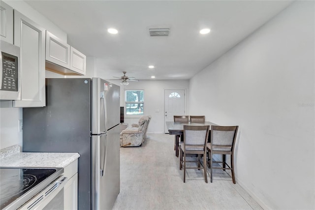 kitchen with light countertops, a ceiling fan, stainless steel microwave, visible vents, and recessed lighting