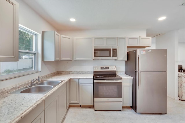 kitchen with a sink, recessed lighting, light countertops, and appliances with stainless steel finishes