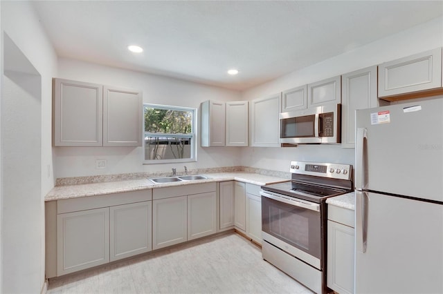 kitchen featuring light countertops, recessed lighting, appliances with stainless steel finishes, a sink, and gray cabinetry
